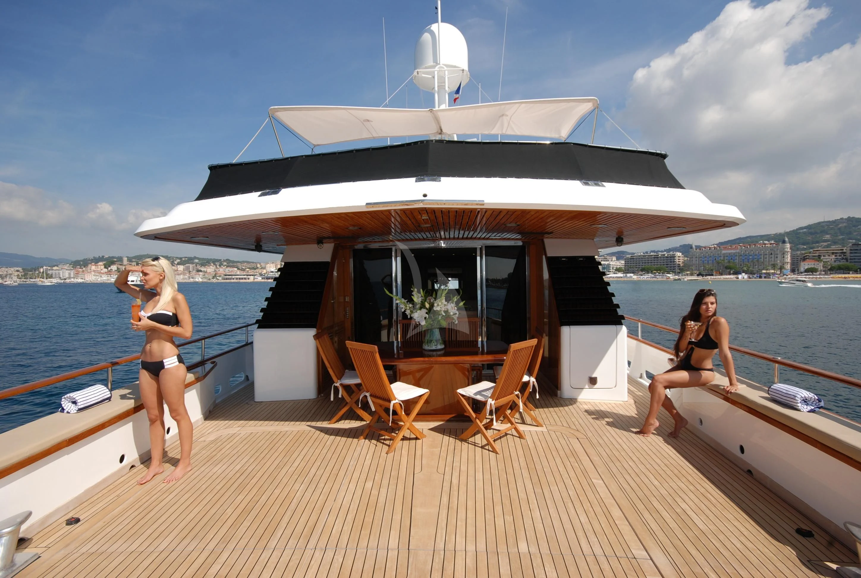a person standing on a deck of a boat with a large white building on the water aboard ATLANTIC ENDEAVOUR Yacht for Charter