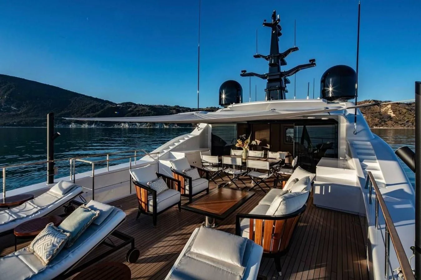 a deck with a deck and chairs on it and a large ship in the water aboard AGORA III Yacht for Sale
