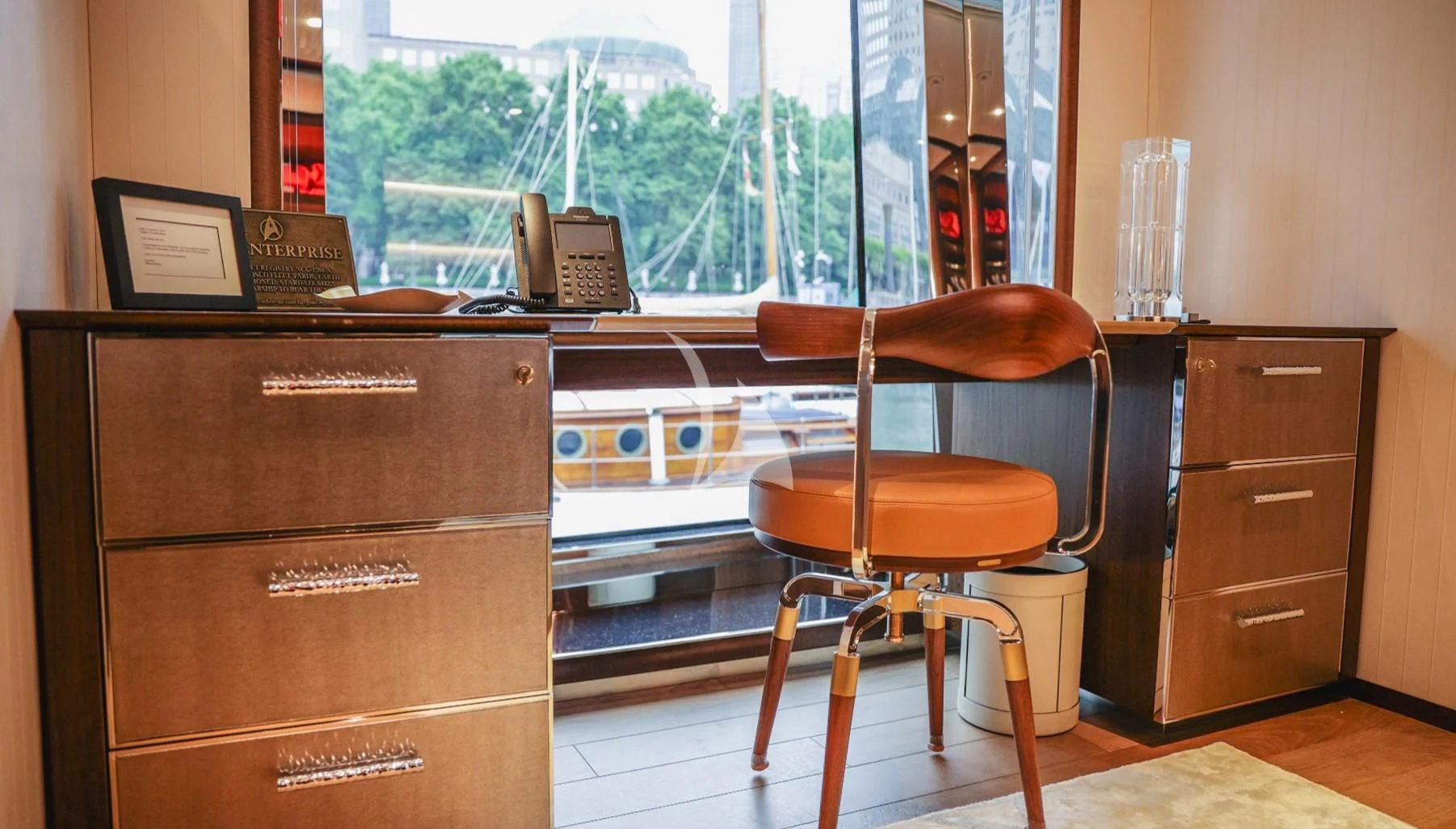 a desk with a computer and a chair in front of a window aboard ENTERPRISE Yacht for Charter