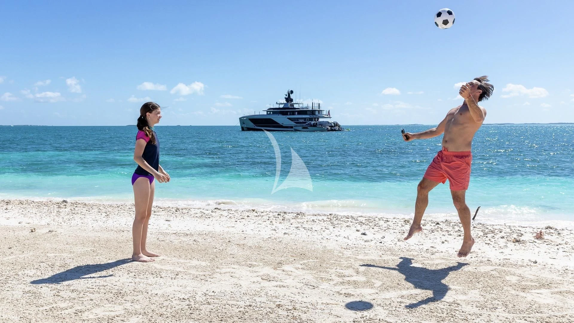 a man and woman playing football on a beach aboard ENTERPRISE Yacht for Charter