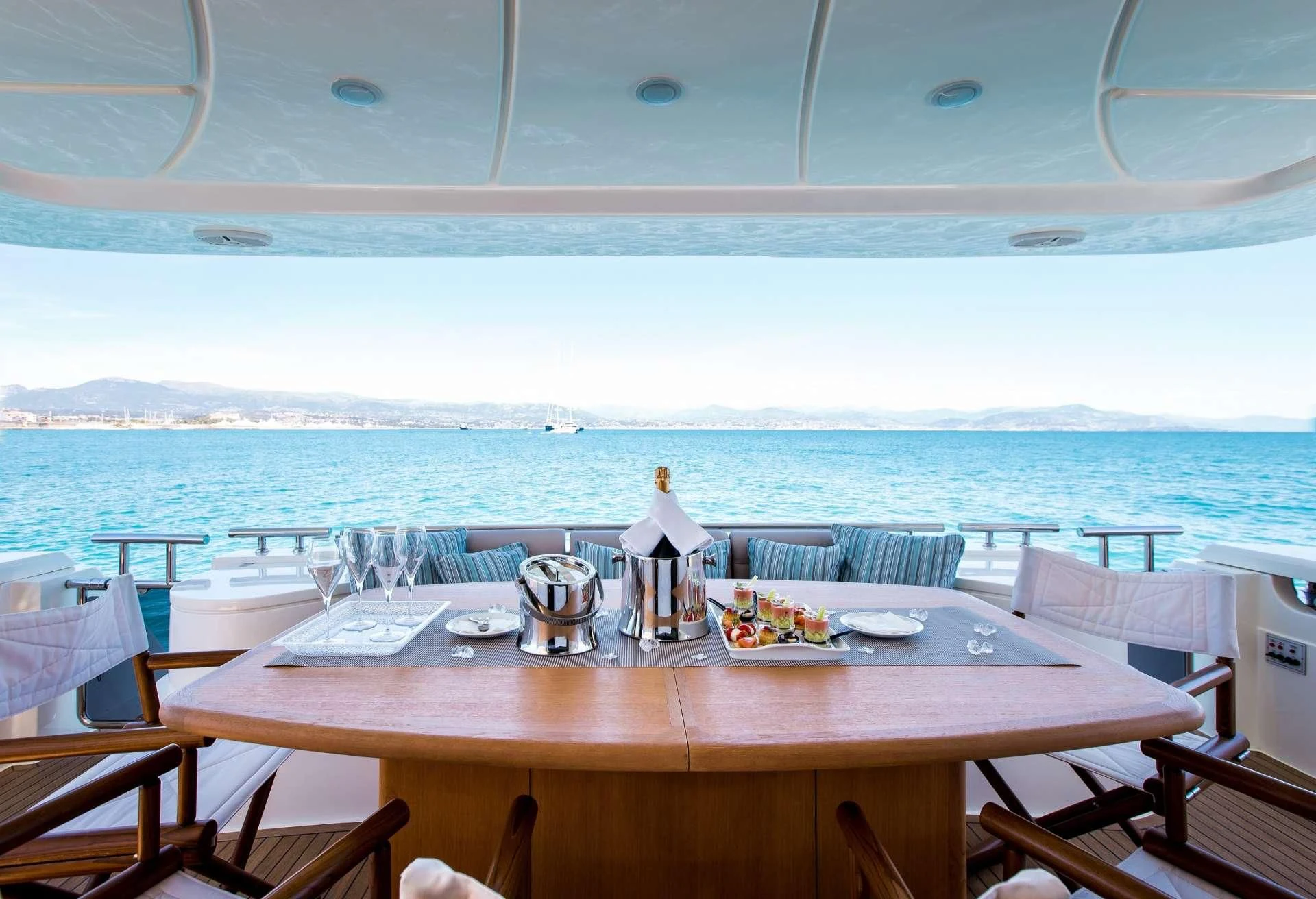 a table with plates and glasses on it by a window with a view of the ocean aboard PIOLA Yacht for Sale