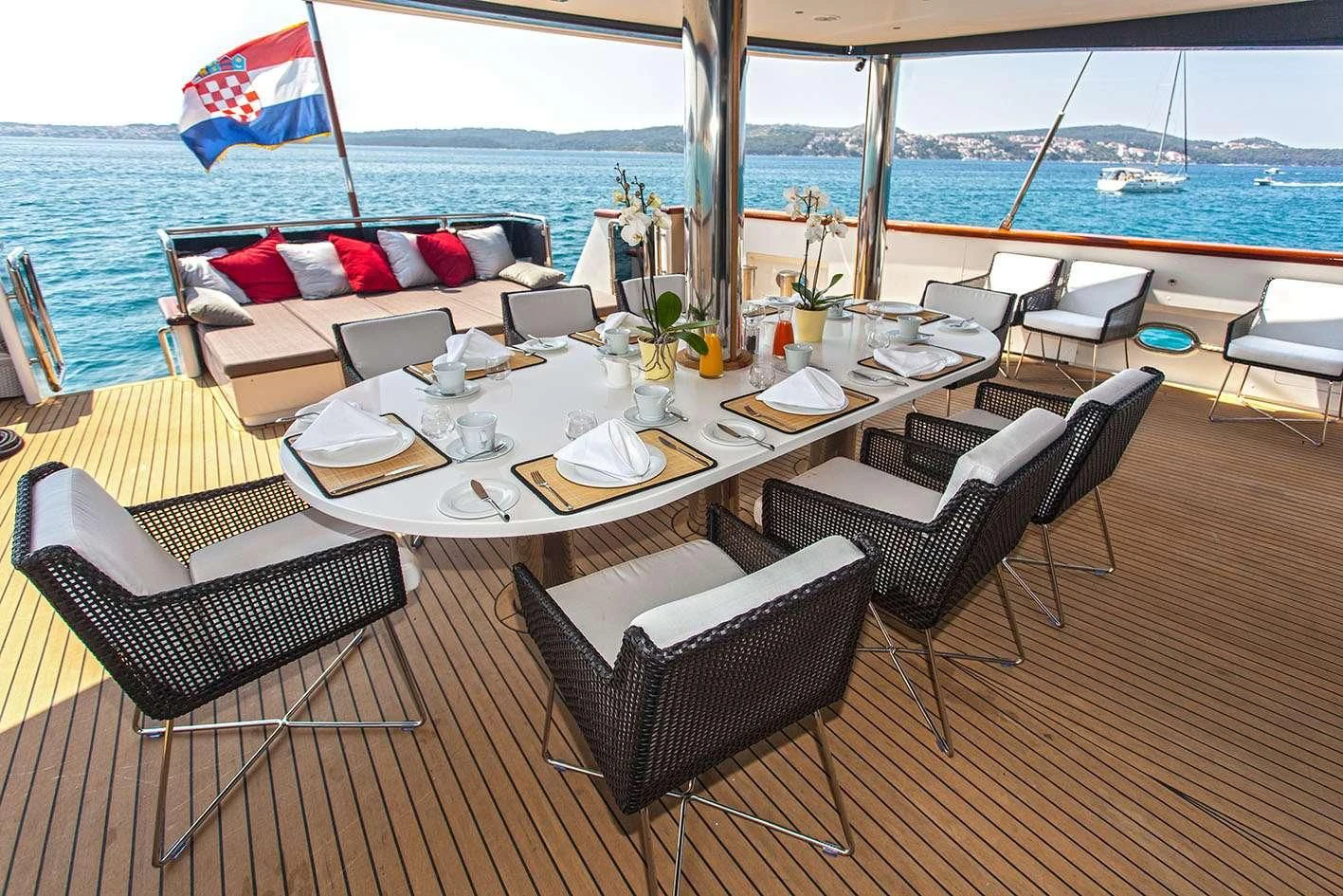 a table set for a meal on a deck overlooking the ocean aboard NAVILUX Yacht for Sale