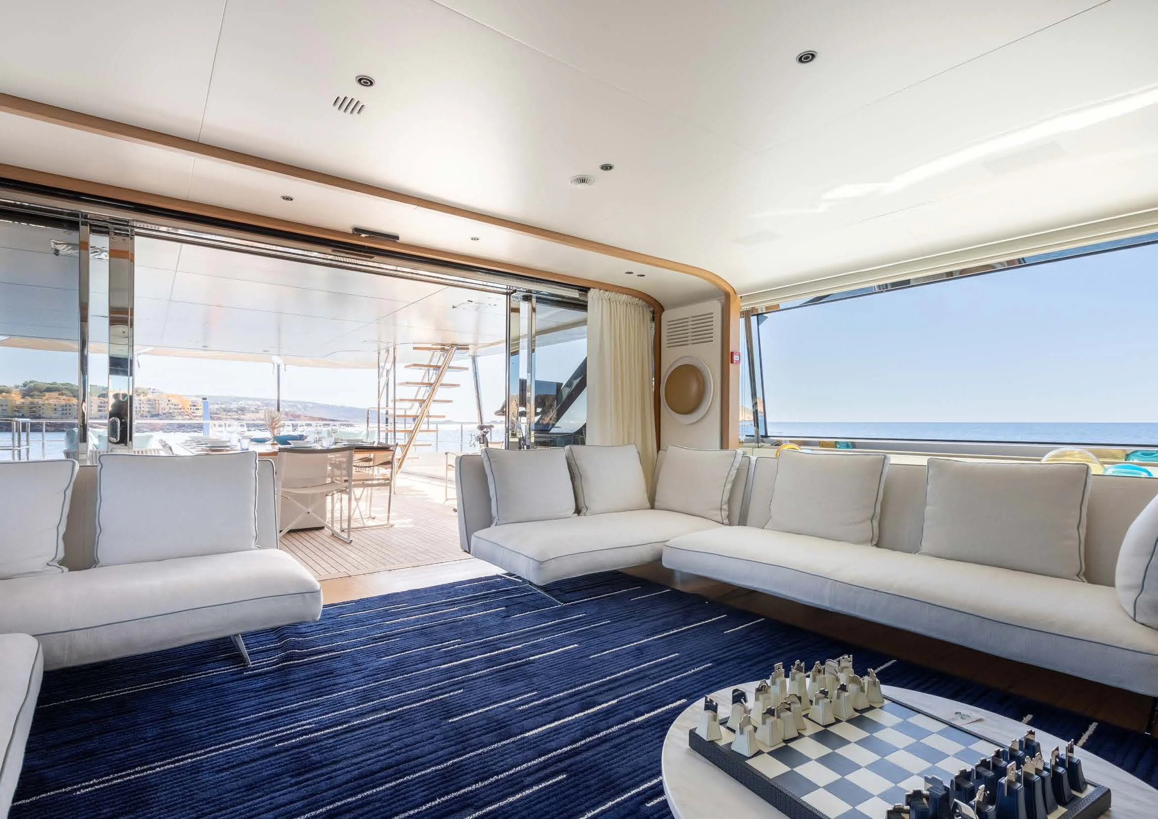 a living room with a large blue rug and white couches aboard EH2 Yacht for Sale