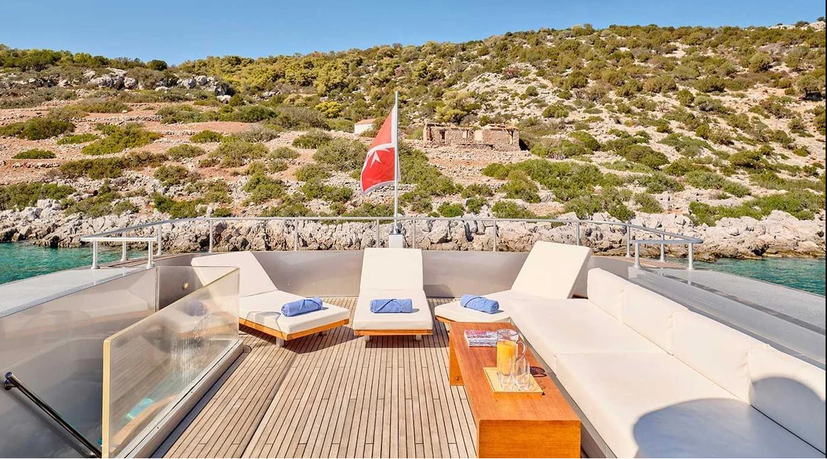 a deck with a flag and a body of water in the background aboard AMICI PER SEMPRE Yacht for Charter