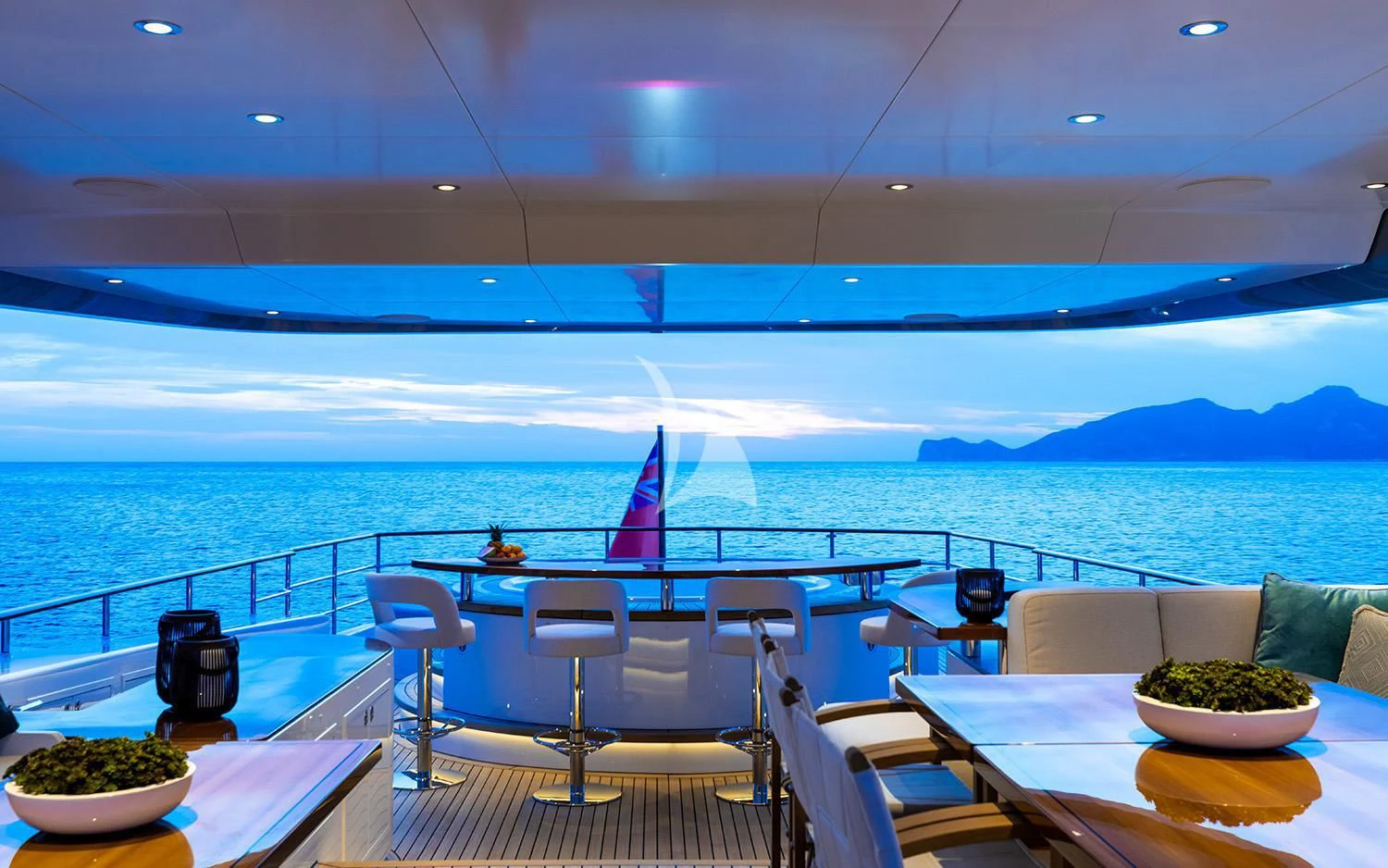 a deck with a table and chairs on it and a body of water in the background aboard CALYPSO I Yacht for Charter
