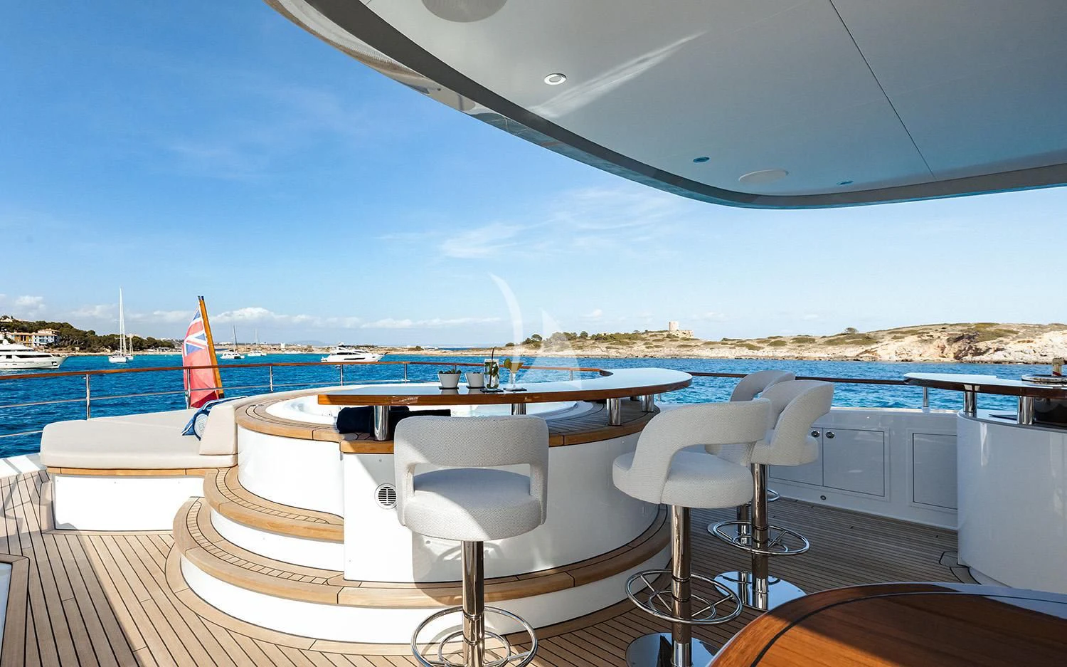 a table and chairs on a deck overlooking a beach aboard CALYPSO I Yacht for Charter