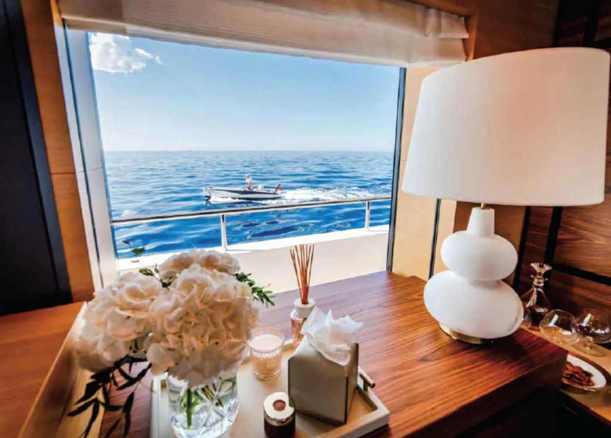 a table with flowers and candles on it by a window with a body of water in the background aboard ALI BABA Yacht for Sale