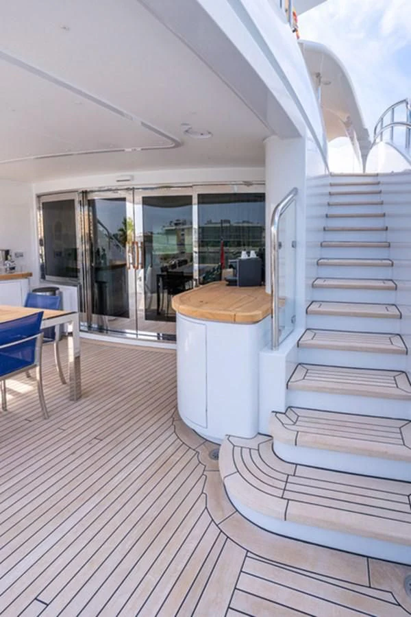 a wood deck with a bench and a table and chairs aboard ALI BABA Yacht for Sale