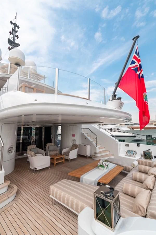 a deck with a flag and a building with chairs and a table aboard ALI BABA Yacht for Sale