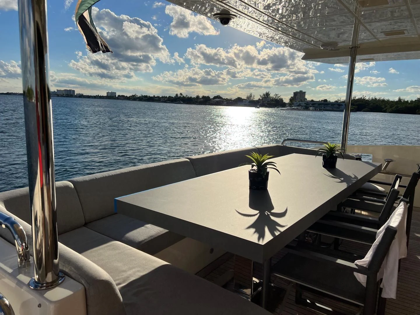 a table with a plant on it by a window with water and a city in the background aboard BT2 Yacht for Sale