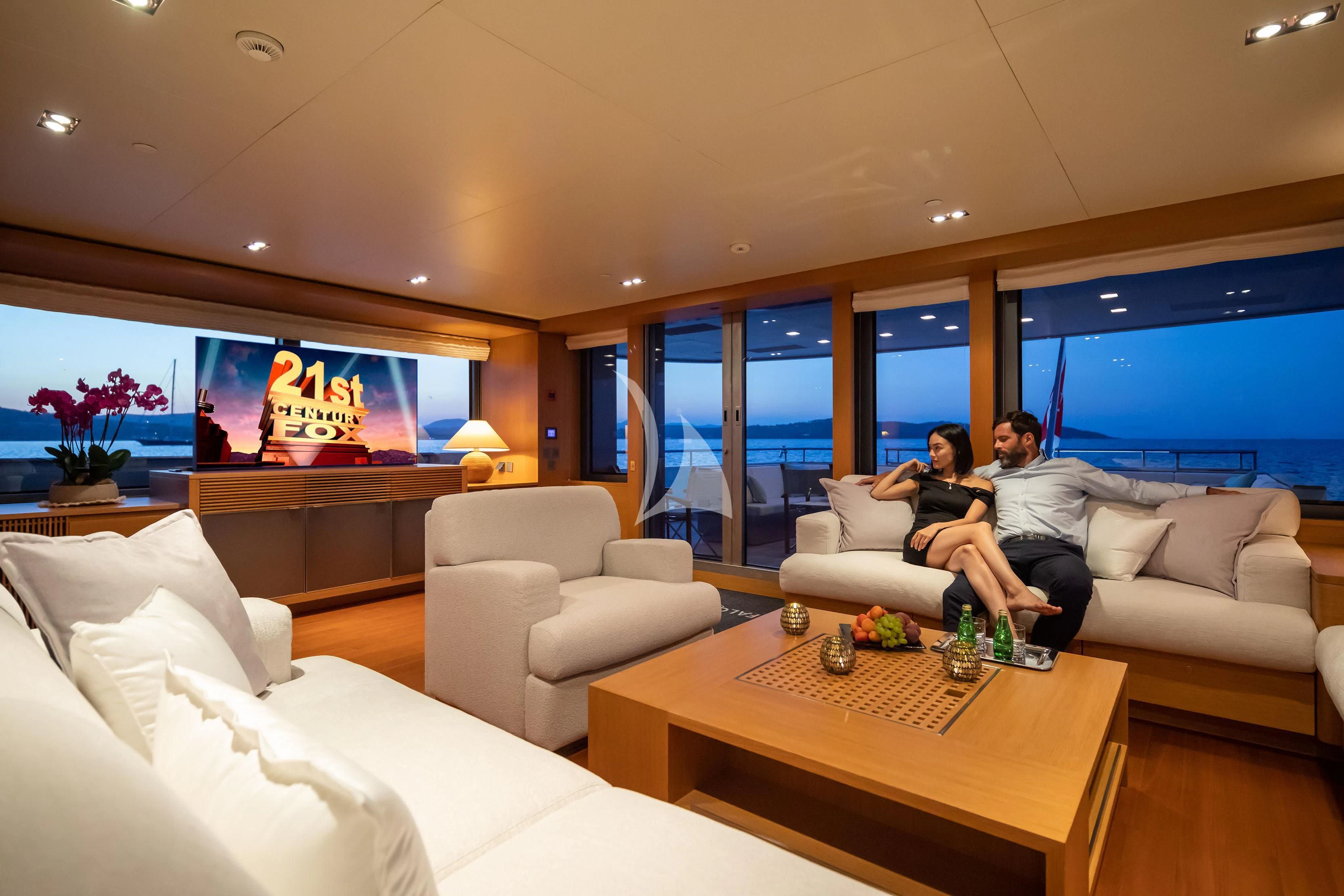 a couple sitting on a couch in a living room with a large tv aboard FALCO MOSCATA Yacht for Sale