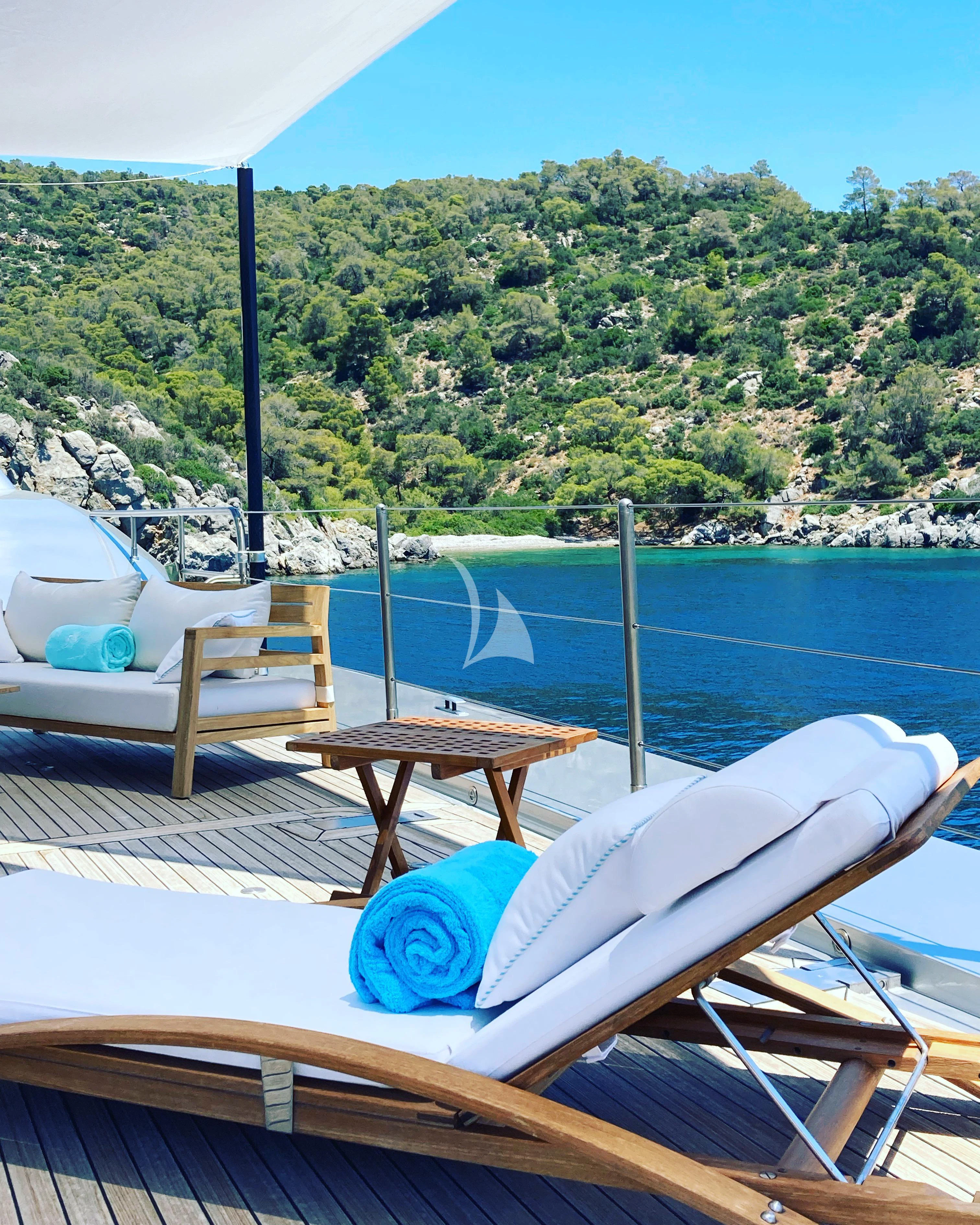 a deck with a table and chairs on it by a body of water aboard FALCO MOSCATA Yacht for Sale