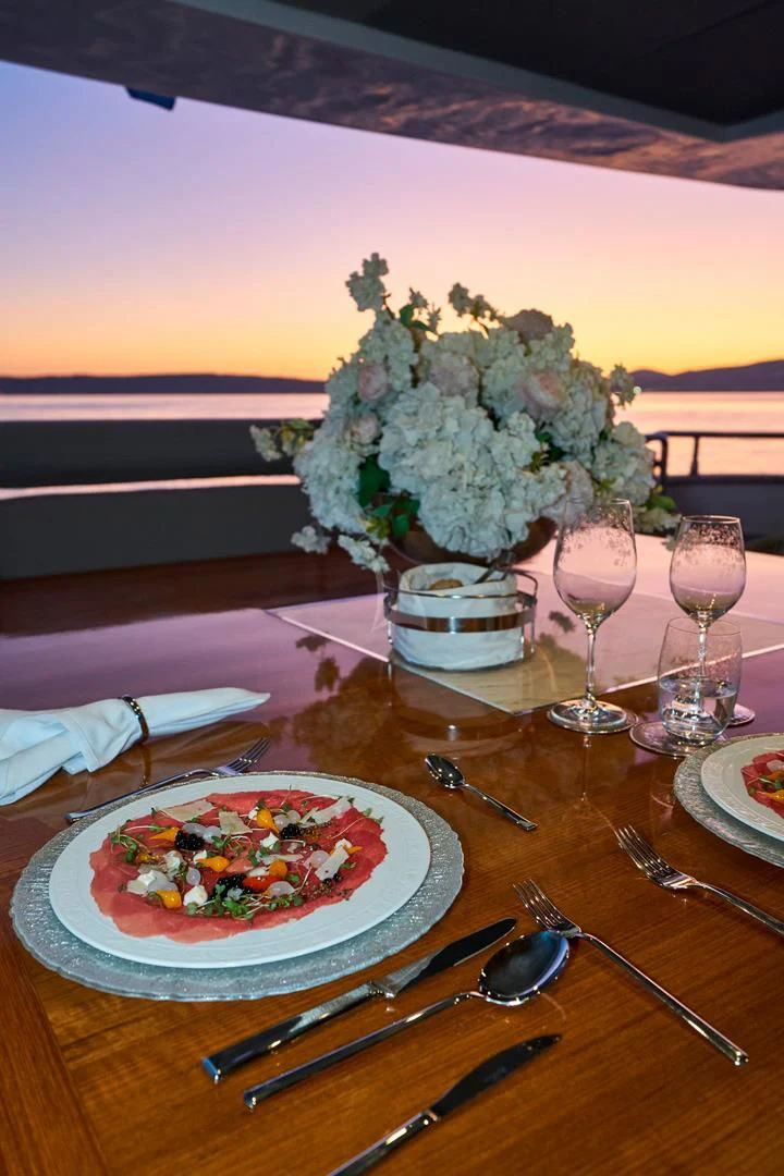 a table with a plate of food and glasses of wine aboard PRINCESS LONA Yacht for Sale