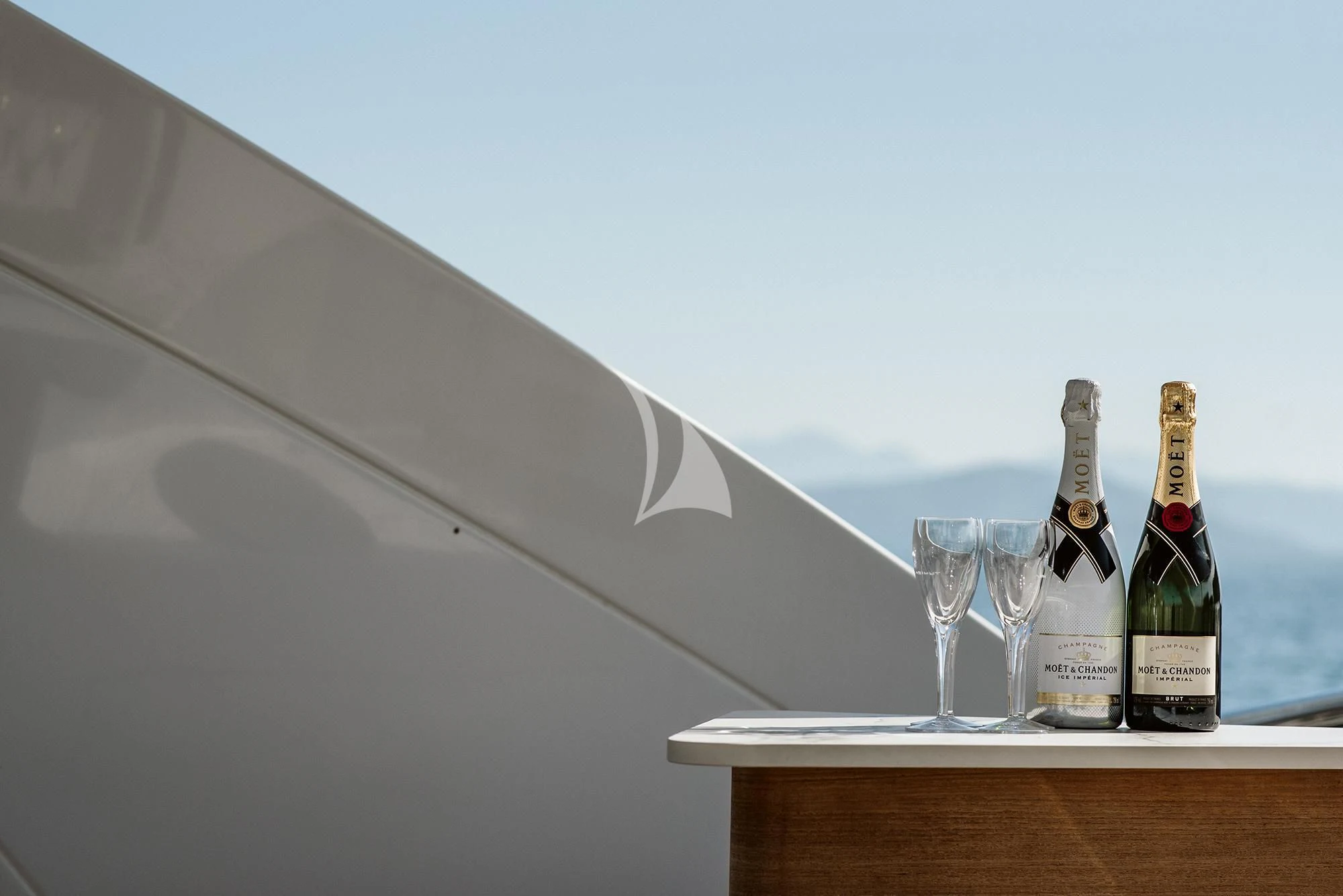 a bottle and glasses on a table aboard AGIO Yacht for Charter
