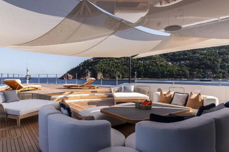 a lounge area with a large white umbrella over it aboard LADY A Yacht for Sale