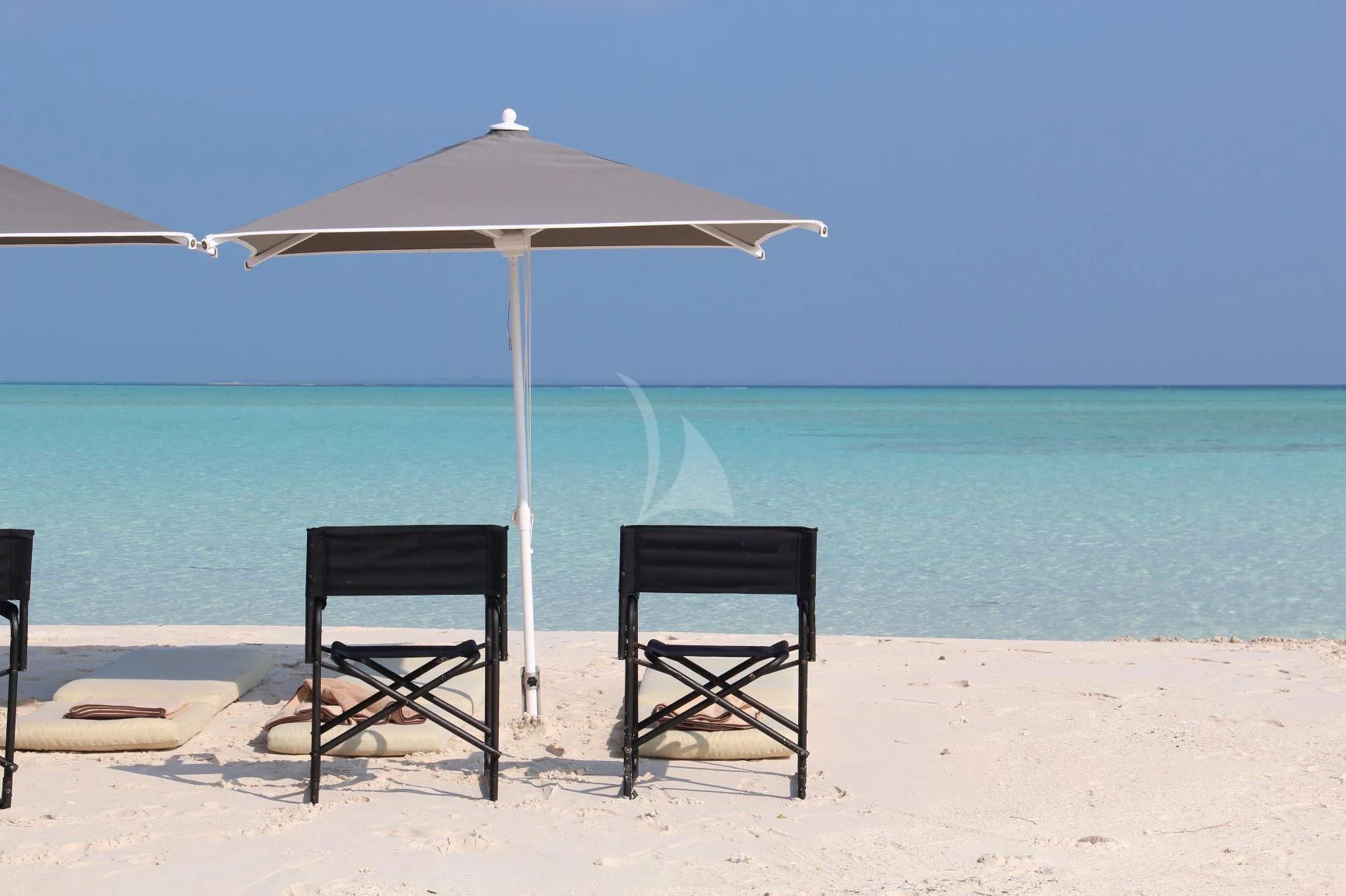 a couple of chairs and an umbrella on a beach aboard LAUREN L Yacht for Sale