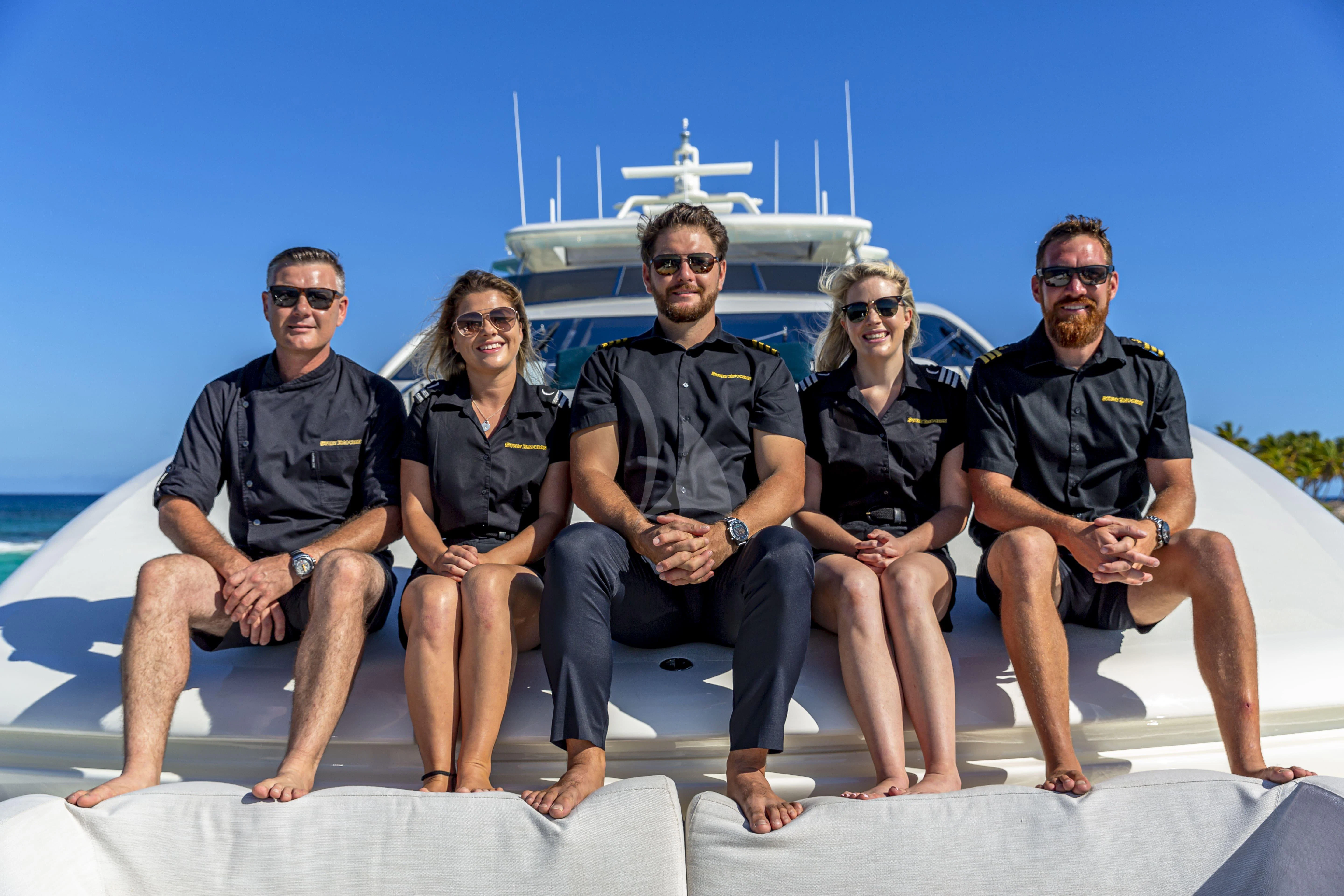 a group of people posing for a photo in front of a boat aboard SWEET EMOCEAN Yacht for Sale