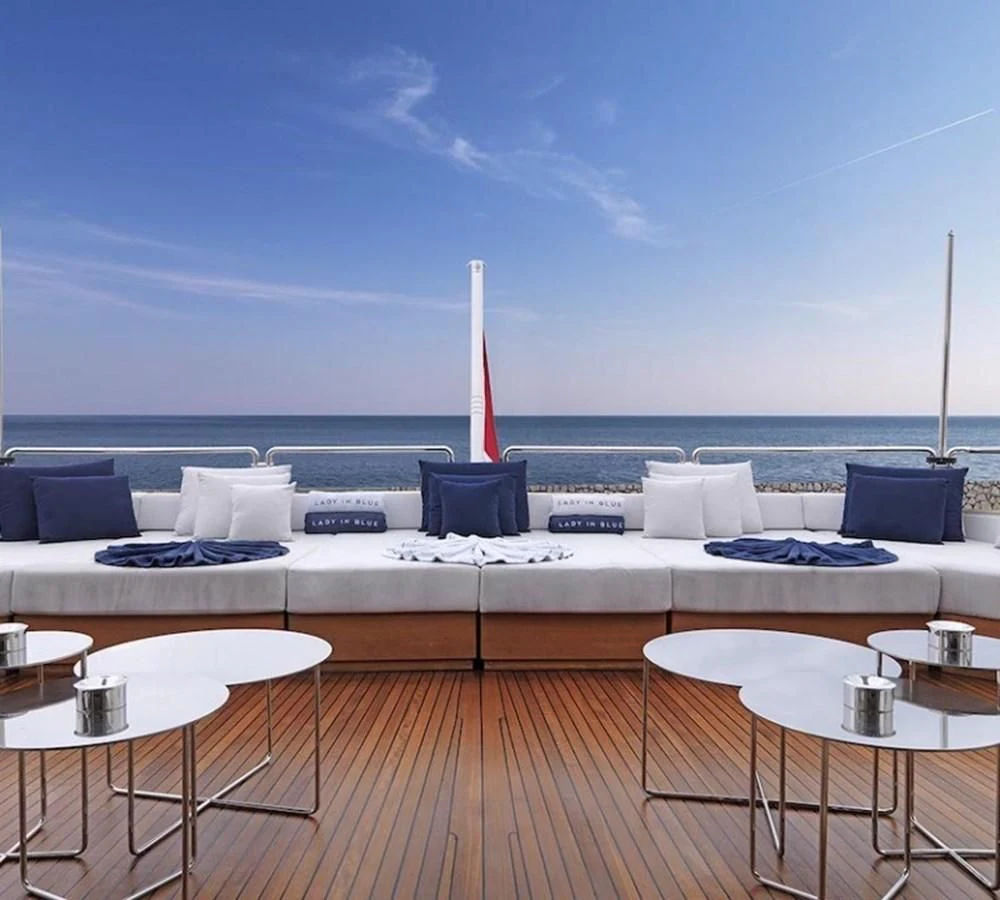a large white couch with a table and chairs on a deck overlooking the ocean aboard LADY IN BLUE Yacht for Sale
