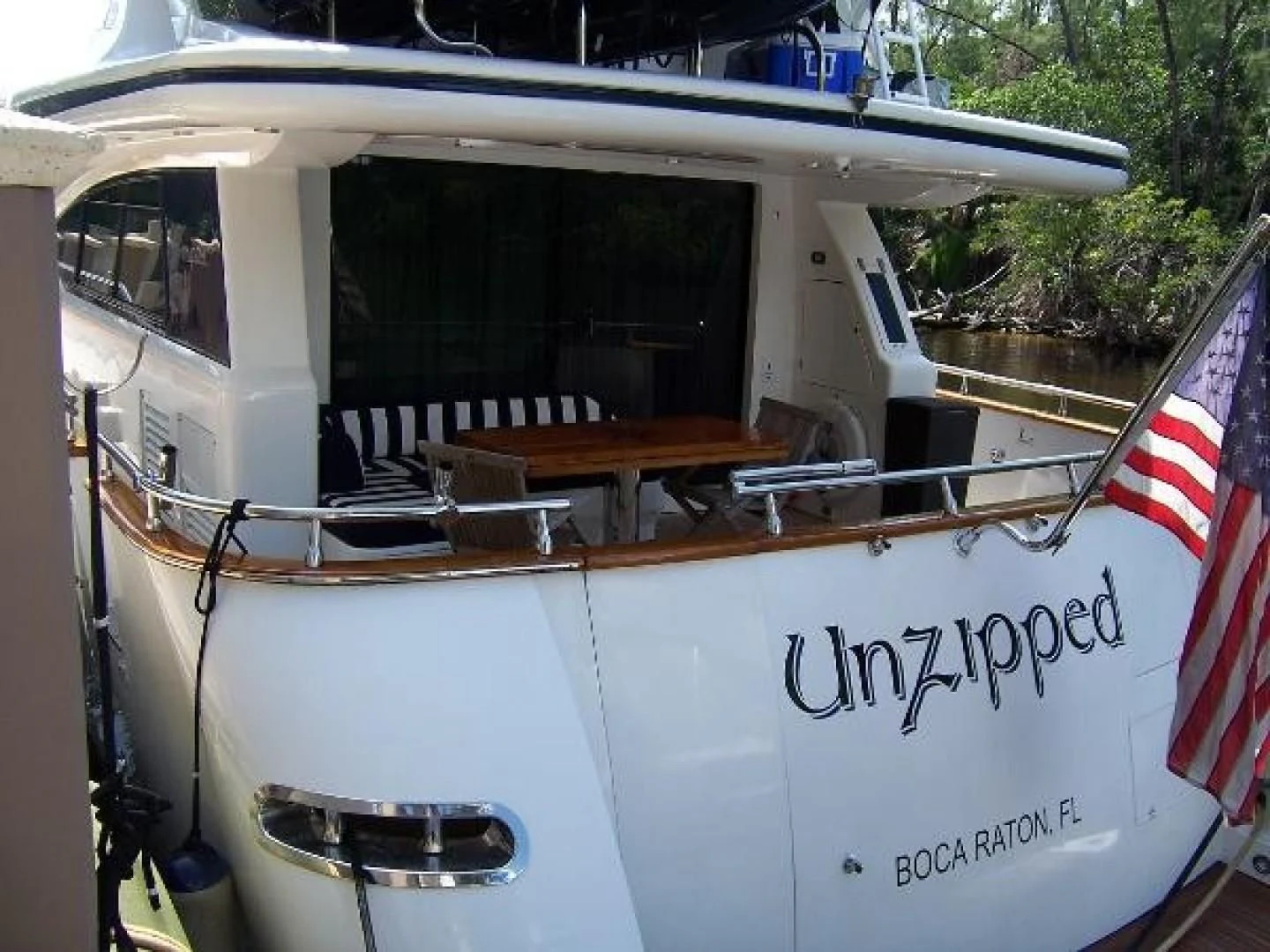 a boat with a flag on the front aboard UNZIPPED Yacht for Sale