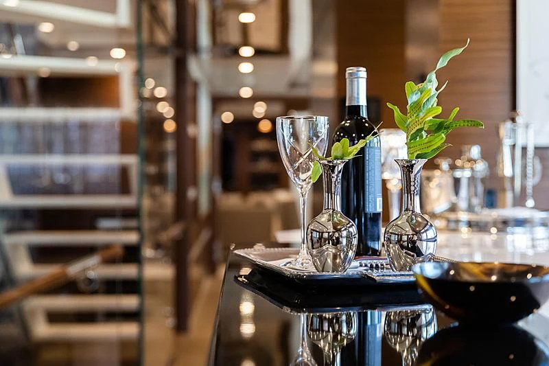 a table with a glass bottle and a glass with a plant in it aboard NORTHLAND Yacht for Sale