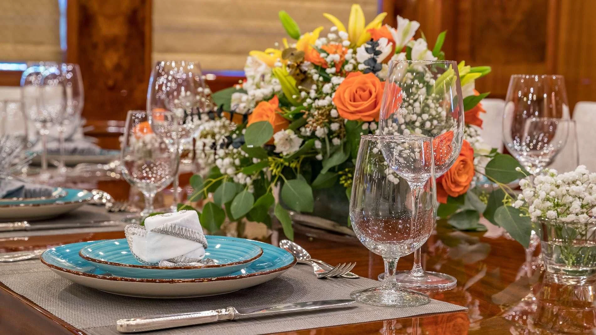 a table with a vase of flowers and glasses on it aboard MAMBO Yacht for Sale