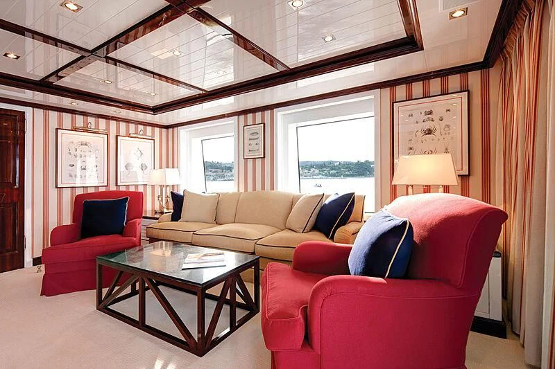 a living room with red chairs and a table aboard OXYGEN Yacht for Sale