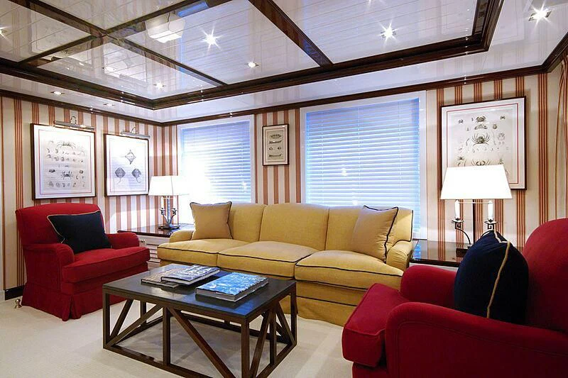 a living room with red couches and a table aboard OXYGEN Yacht for Sale
