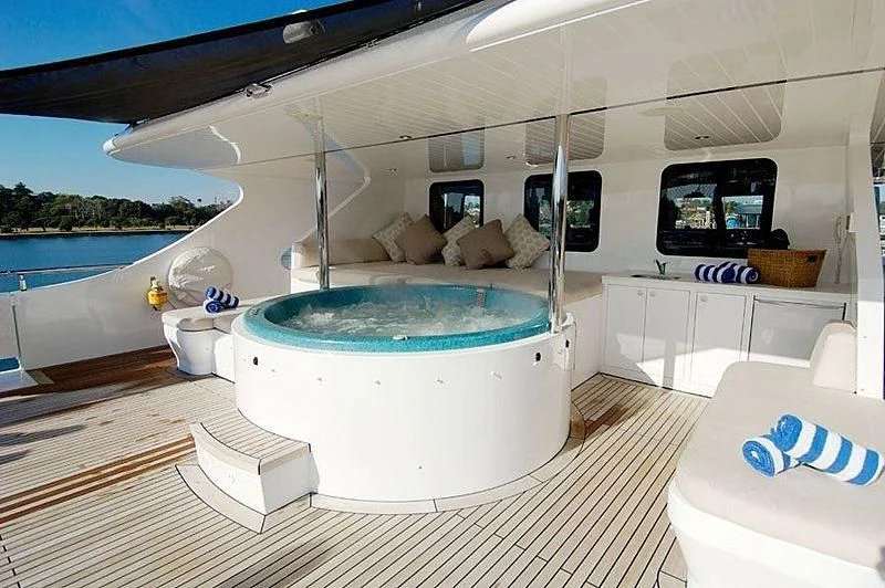 a large white lounge chair next to a pool with a large white round table and a white chair aboard TANGO Yacht for Sale