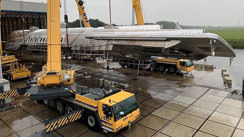 a large yellow truck next to a plane aboard PHI Yacht for Sale