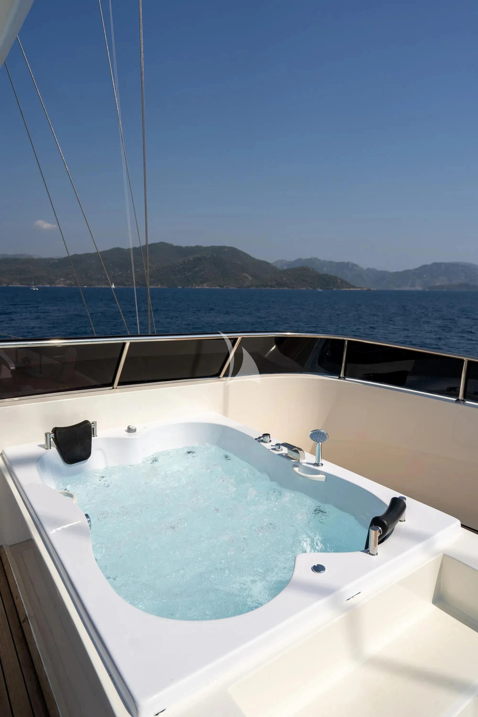 a bathtub with a view of the ocean and mountains in the background aboard DE LOVE Yacht for Charter