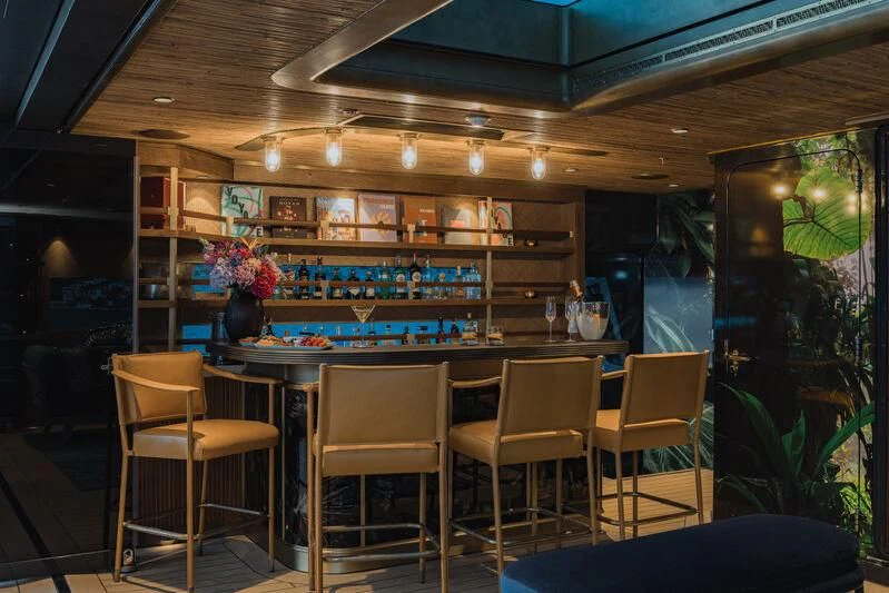 a room with a table chairs and a bar aboard PINK SHADOW Yacht for Sale