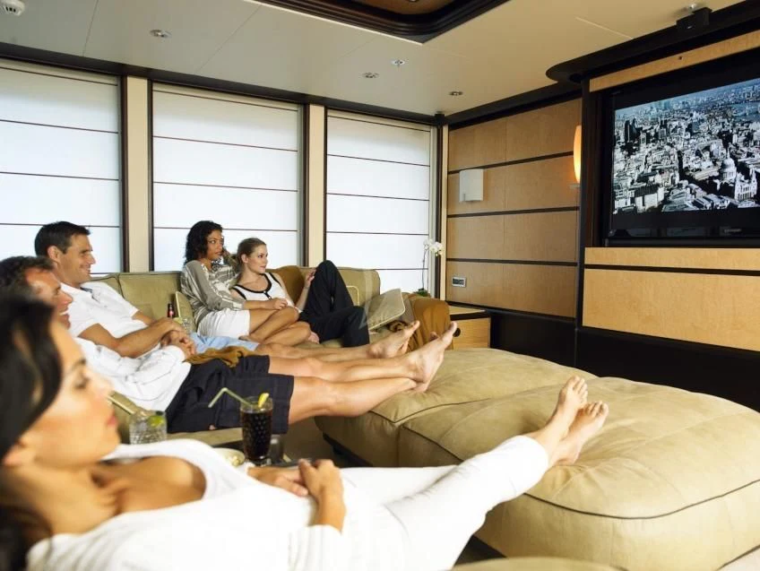 a group of people sitting on a couch watching a television aboard HARLE Yacht for Sale