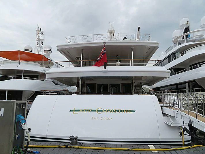 a large white boat with a red flag on it aboard LADY CHRISTINE Yacht for Sale