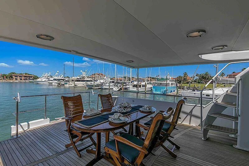 a deck with chairs and tables on it by a body of water aboard LA VIDA Yacht for Sale