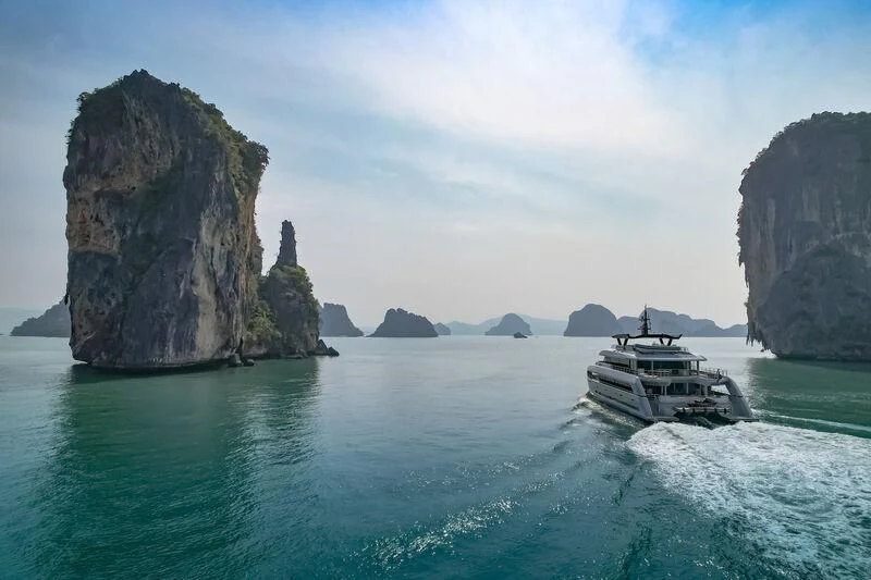 a boat sailing in the sea with Ha Long Bay in the background aboard SPACECAT Yacht for Sale