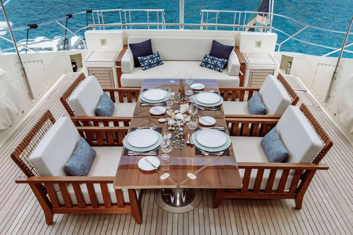 a table with plates and chairs on a deck with a view of the water aboard VANTAGE Yacht for Sale