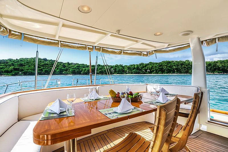 a table set for a meal on a deck overlooking a body of water aboard INFINIUM Yacht for Sale