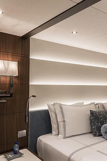 a bed with a white pillow and a blue bottle on a table aboard JODI ANN Yacht for Charter