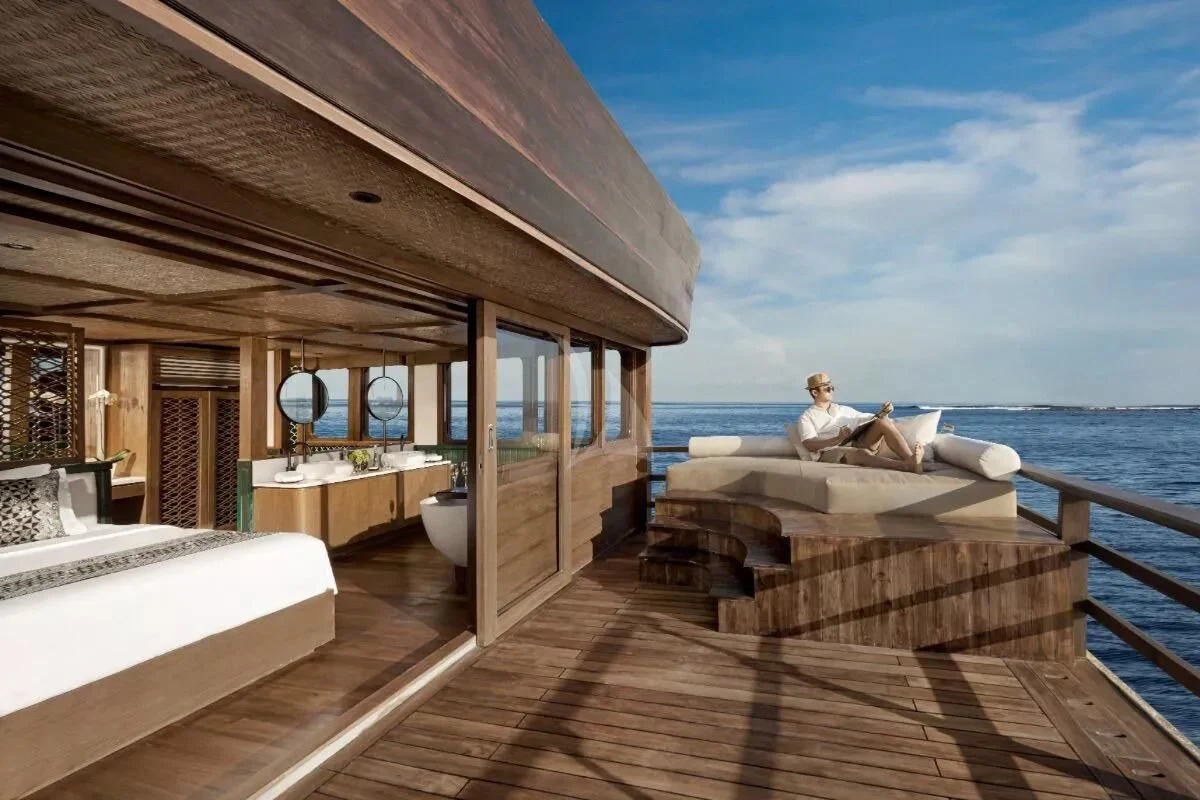 a person sitting on a bed on a deck overlooking the ocean aboard SAMSARA SAMUDRA Yacht for Sale