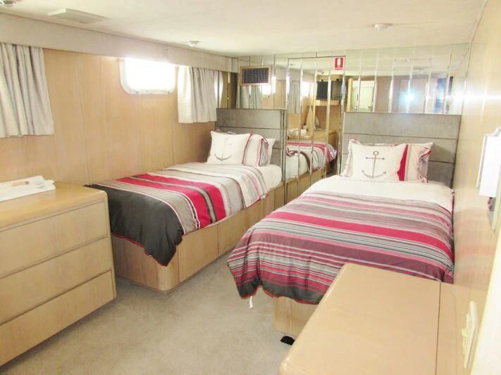 a room with beds and a dresser aboard GOOD NEWS Yacht for Sale