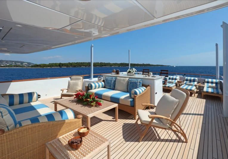 a deck with chairs and a table on it aboard HELIOS 2 Yacht for Sale