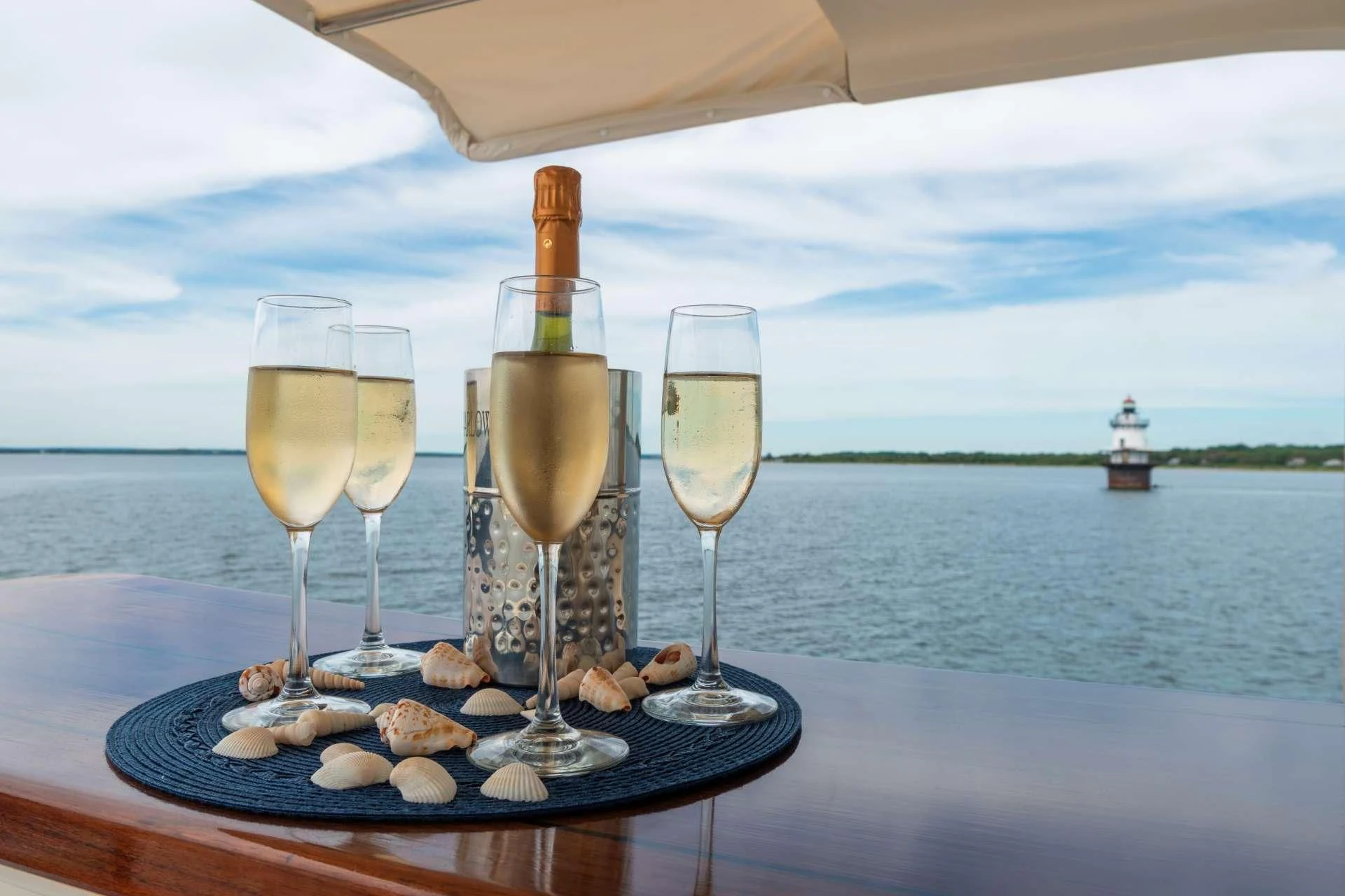 a group of glasses of champagne on a tray with rocks and a body of water in the background aboard HALCYON SEAS Yacht for Sale