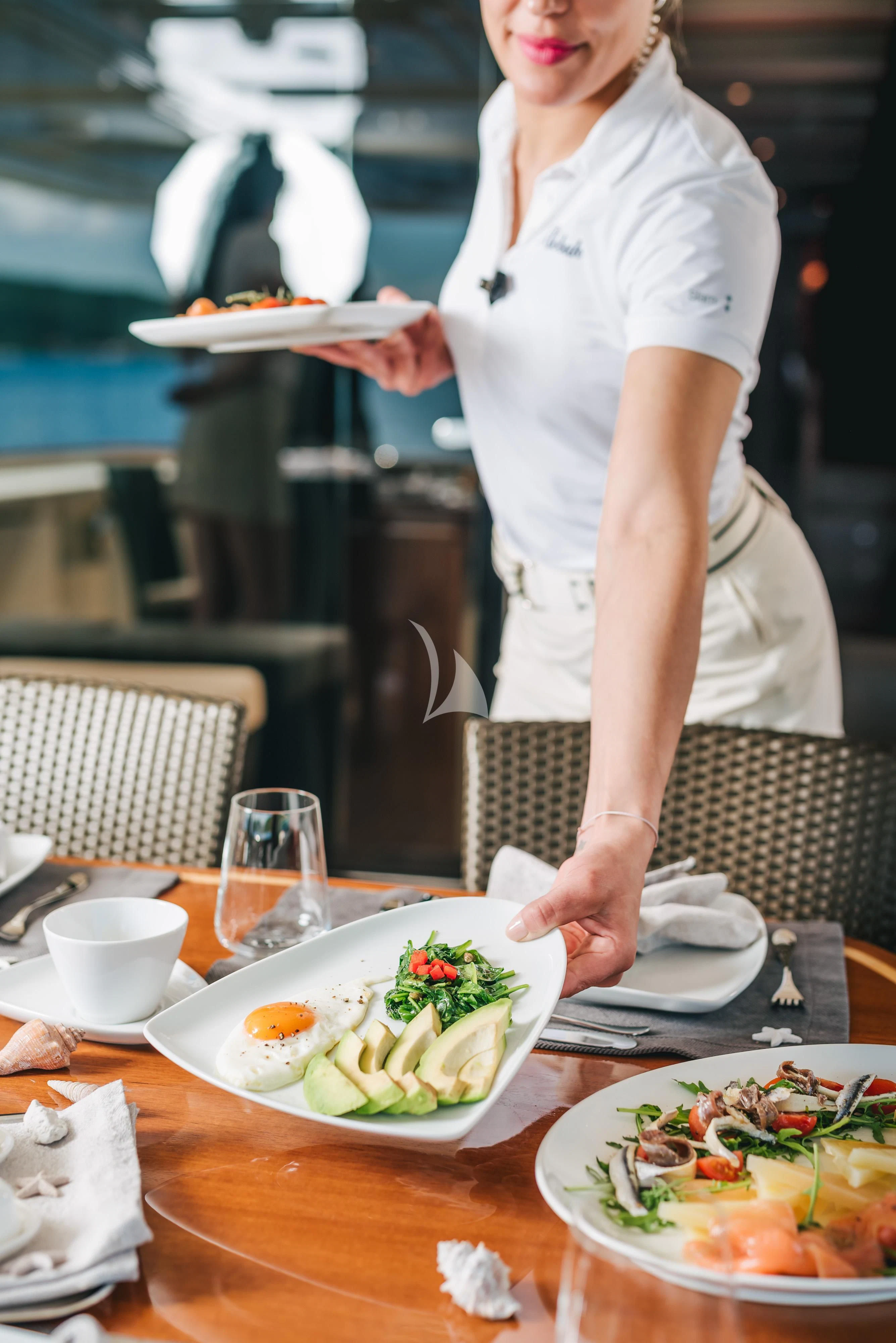 a chef holding a plate of food aboard KLOBUK Yacht for Charter