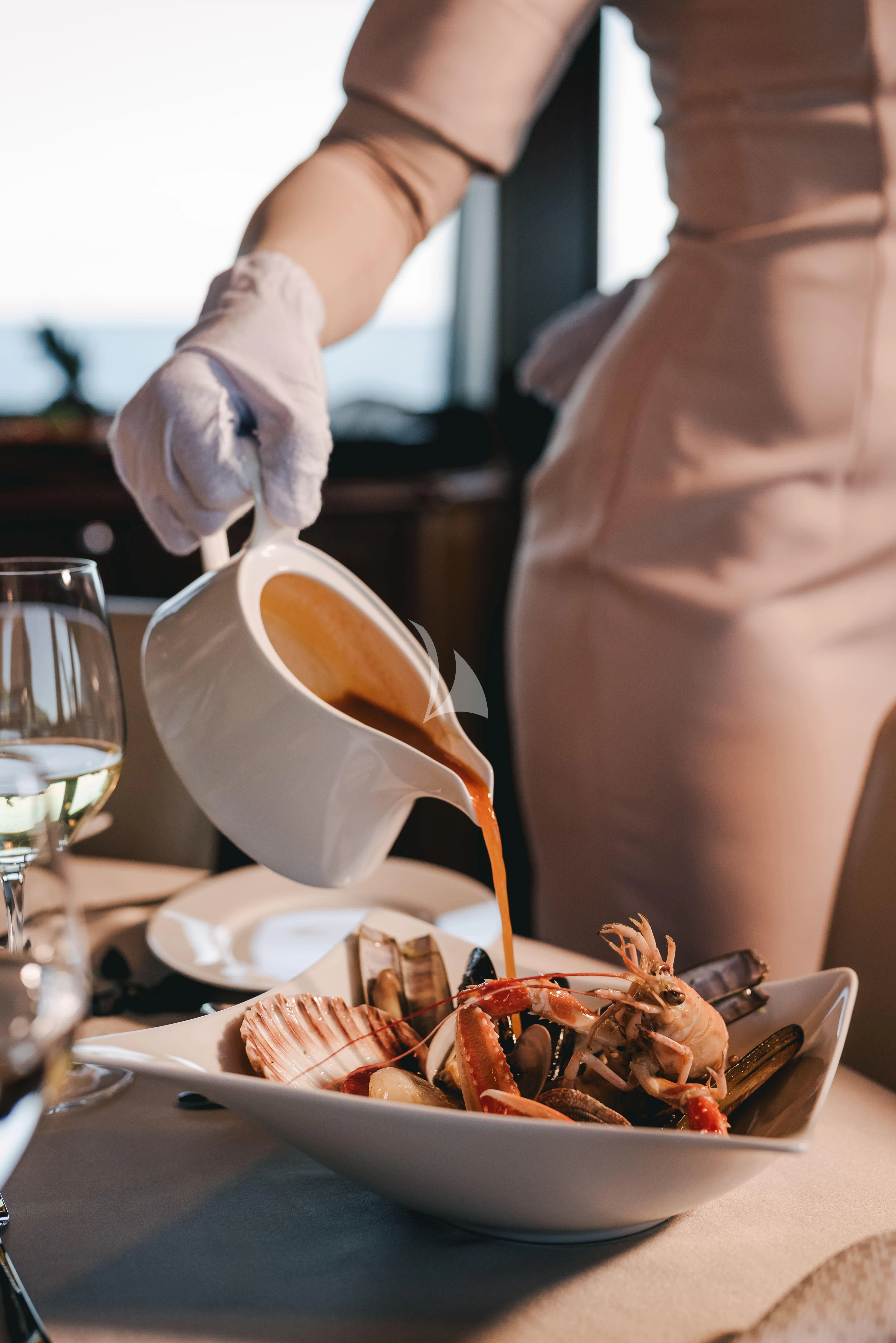 a person pouring a liquid into a bowl of food aboard KLOBUK Yacht for Charter