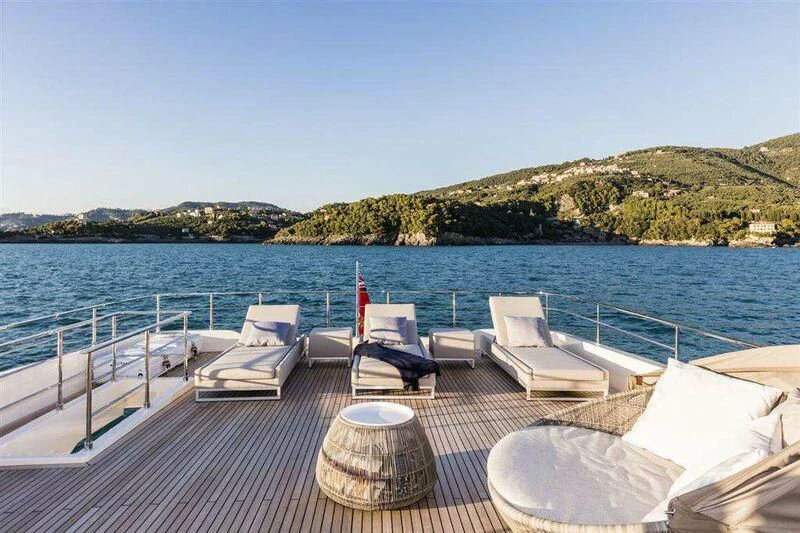 a deck with chairs and a body of water in the background aboard MIKIL Yacht for Sale