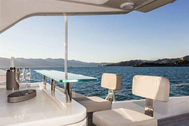 a table and chairs on a deck overlooking a body of water aboard MIKIL Yacht for Sale