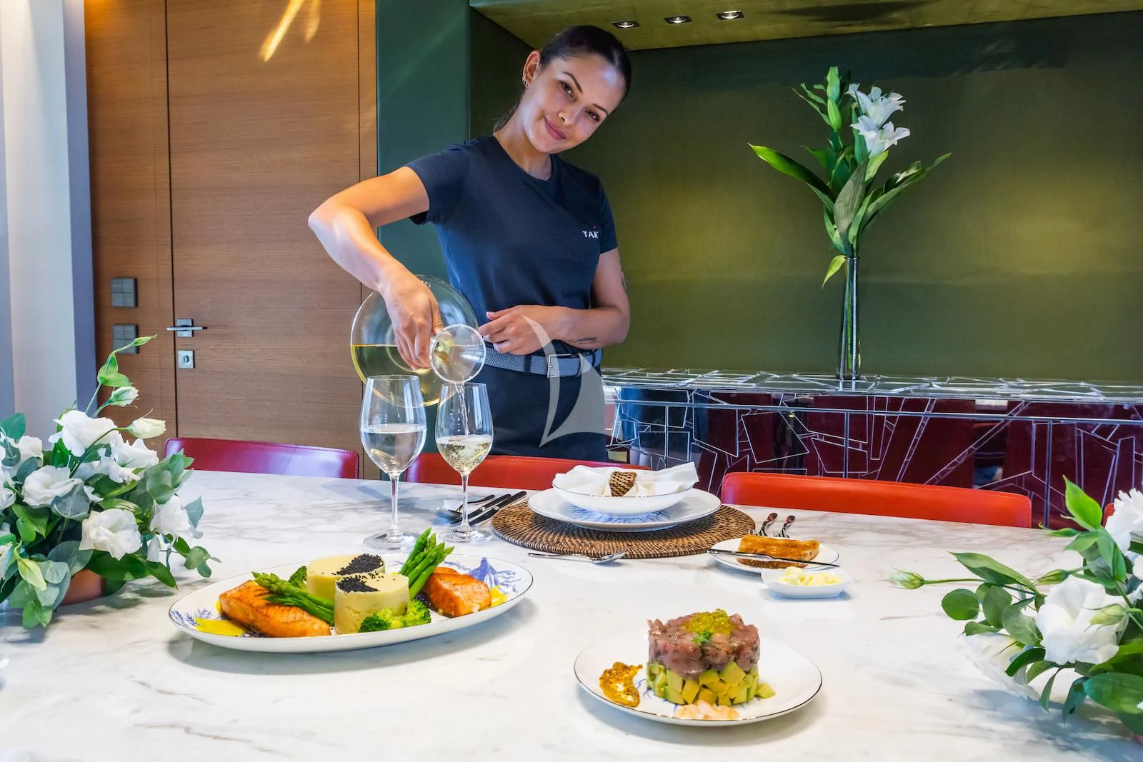 a woman pouring wine into a glass aboard TAKARA ONE Yacht for Charter