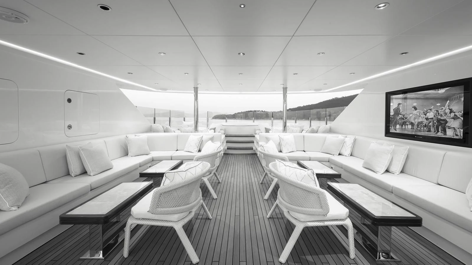 a room with white chairs and a table with a couch and a television on the wall aboard RASHA Yacht for Sale