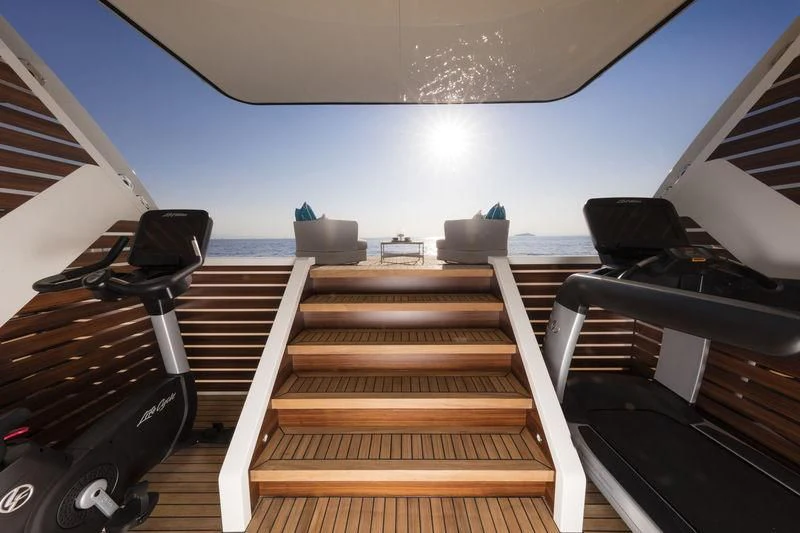 a wooden deck with a view of the ocean and the sun aboard RASHA Yacht for Sale