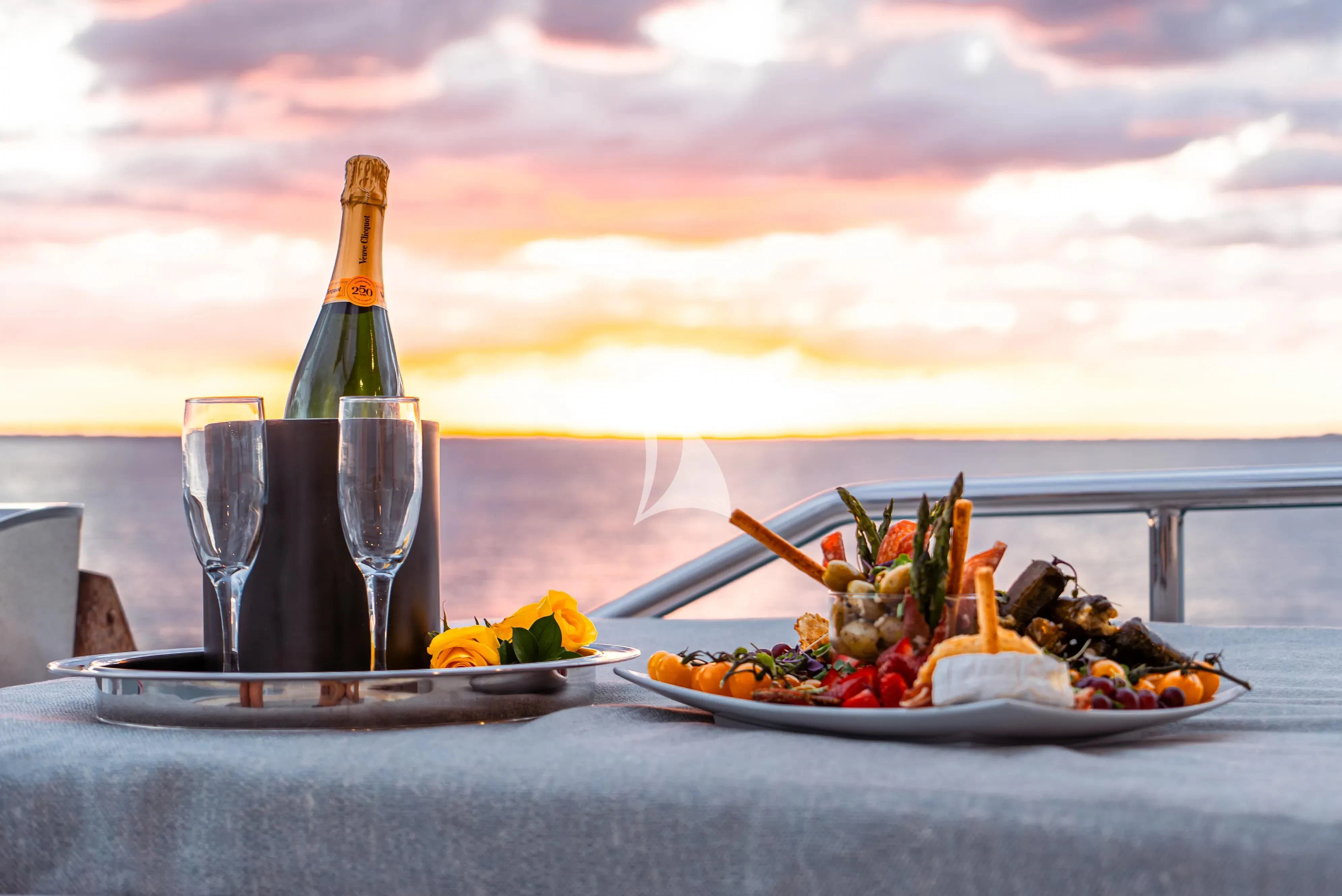 a bottle of champagne and a plate of food on a table aboard BRANDI WINE Yacht for Charter